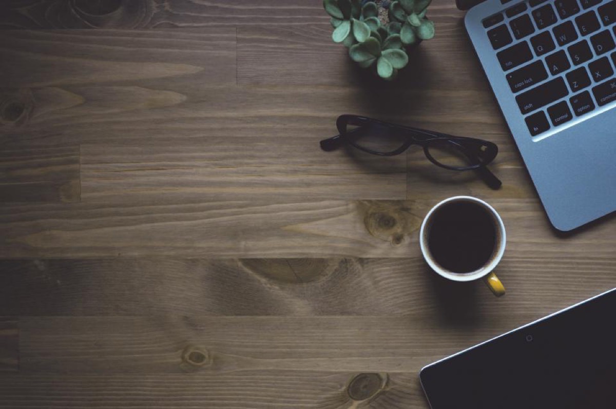 A laptop and a cup of coffee on a wooden desk